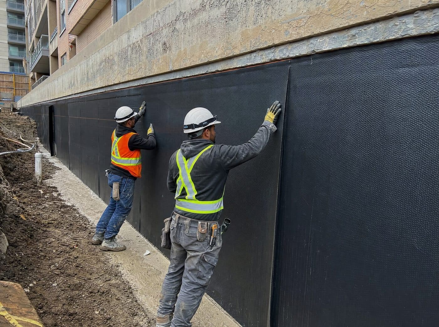 CWC Commercial Waterproofing crew installing below-grade membrane at a multi-unit site