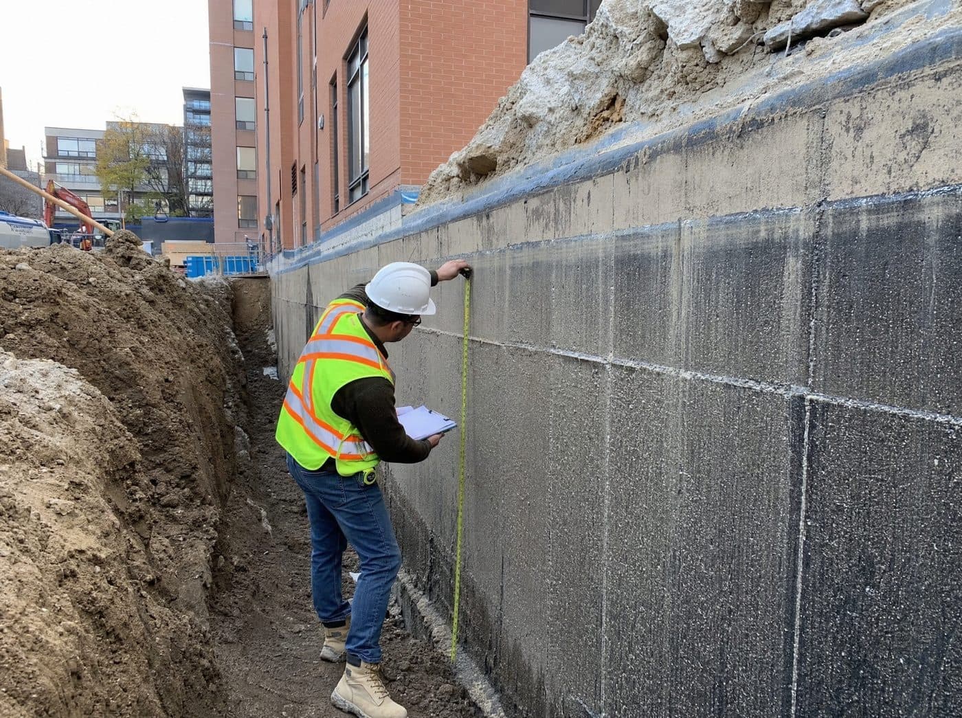 Waterproofing estimator measuring a commercial foundation wall during a GTA site assessment