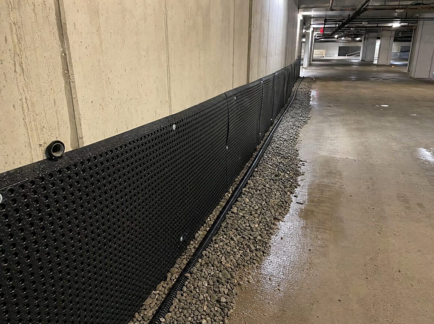Commercial parkade basement drainage trench with dimple membrane and weeping tile in Toronto